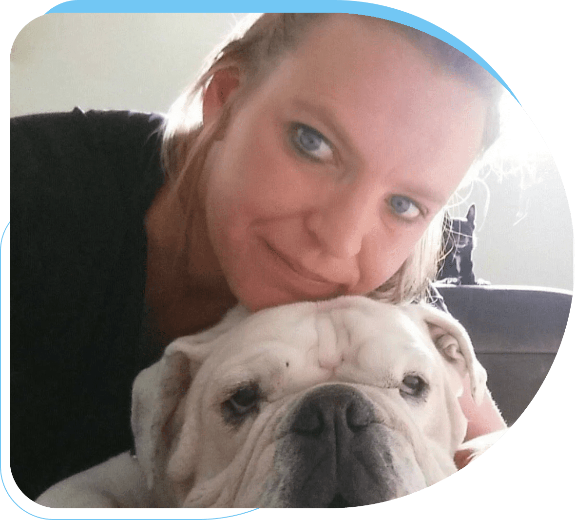 Woman gently resting her face on a white bulldog's head.